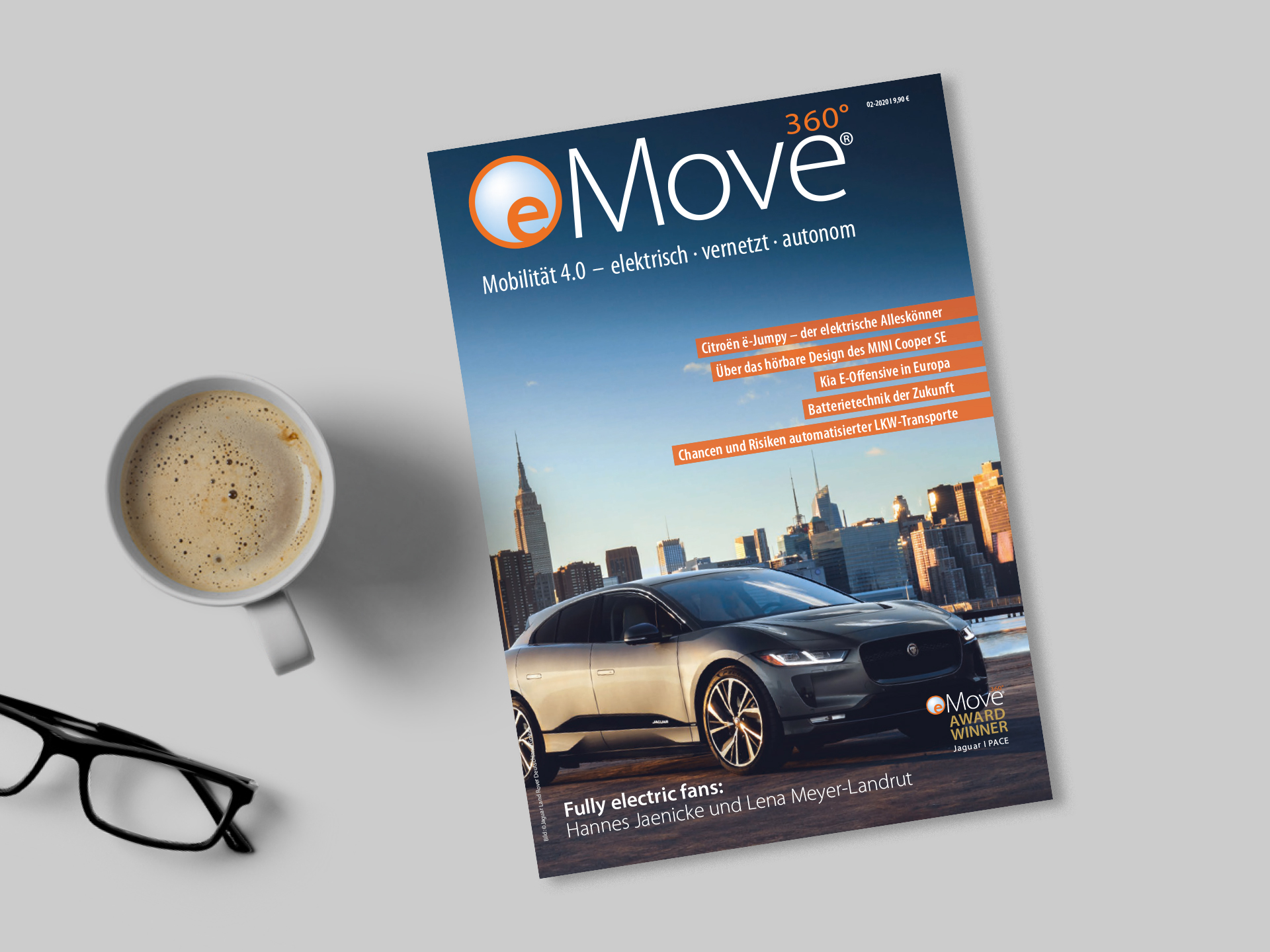 Das Magazin eMove360 Grad liegt auf einem Tisch neben einer Kaffeetasse und einer Brille